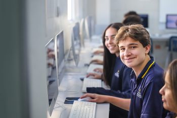 talentoso joven-sonriendo-a-la-camara-en-laboratorio-de-clases-lux-mundi